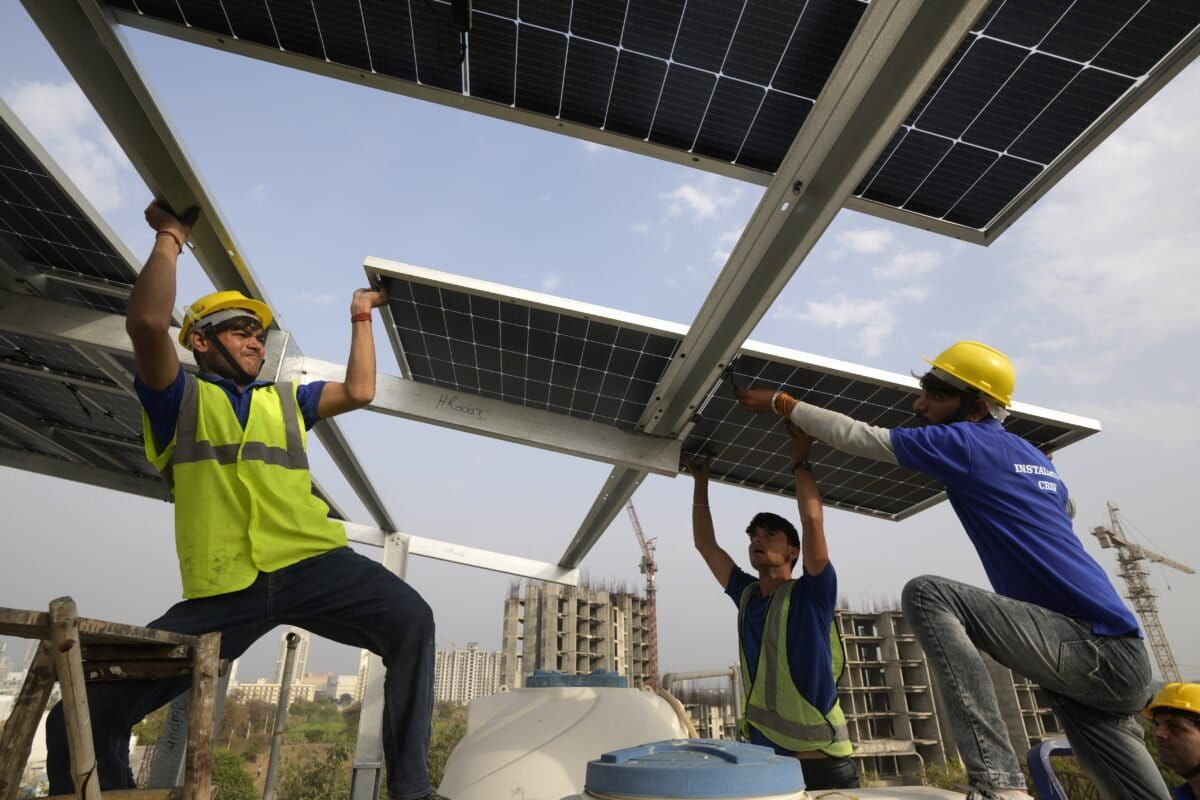 Workers place a panel on the rooftop of a residence in Gurugram. (AP Photo/Manish Swarup)
