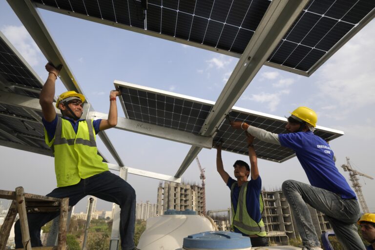 Workers place a panel on the rooftop of a residence in Gurugram. (AP Photo/Manish Swarup)