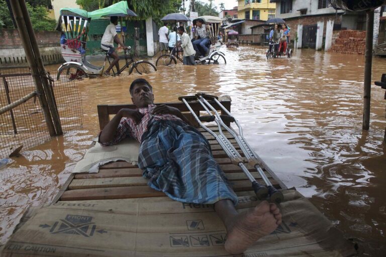 A physically disabled man rests as commuters cross a waterlogged street in 2013 in Guwahati. (AP Photo/Anupam Nath)