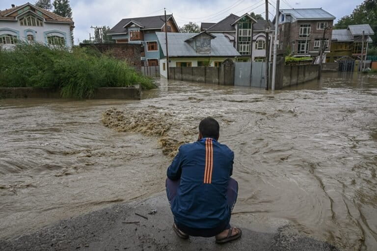A man looks at a house submerged in floodwaters on the outskirts of Srinagar, Kashmir. Image by Abid Bhat.