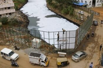 Workers install metal mesh sheets on the banks of Bellundur Lake to prevent industrial pollution from spilling on to the road in Bangalore. (AP Photo/Aijaz Rahi)