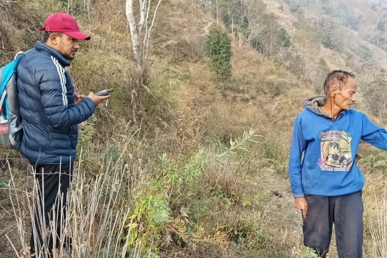 A field team member consults with a local landowner while demarcating the boundaries of a potential restoration site in the hills. Image by Aditya Pradhan.