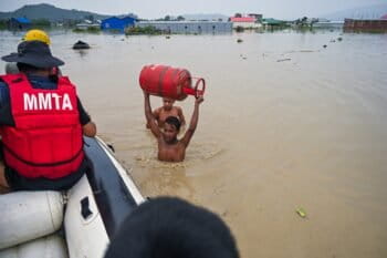 A boy carries a gas cylinder to a rescue boat from his inundated kitchen in Mantripukhri, Imphal East district in June 2024. Image by Ningthoujam Victor.