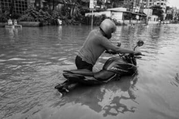 A man pushing his motorbike in a flood in West Bengal.