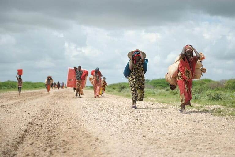 Women migrate with their possessions to a camp in Somalia, after being forced out of their homes due to heavy rains and disputes. Image by Tobin Jones via Flickr (Public Domain).