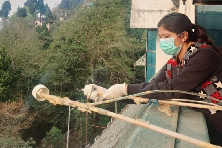 Doctoral researcher Antara Pramanick installs an air sample collection instrument at the Darjeeling hilltop. Image by Sanat Kumar Das.