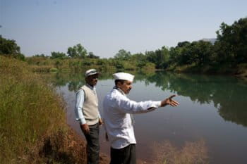 Gunjavane’s sarpanch, Laxman Rasal (R), and Raintree Foundation field officer Pravin Sanga Shetty at a desilted and revived percolation tank that stores rainwater flowing down from surrounding hills and gradually recharges nearby wells. Image by Saumitra Shinde/Mongabay.