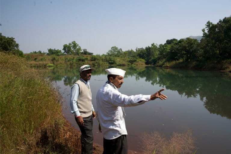 Gunjavane’s sarpanch, Laxman Rasal (R), and Raintree Foundation field officer Pravin Sanga Shetty at a desilted and revived percolation tank that stores rainwater flowing down from surrounding hills and gradually recharges nearby wells. Image by Saumitra Shinde/Mongabay.