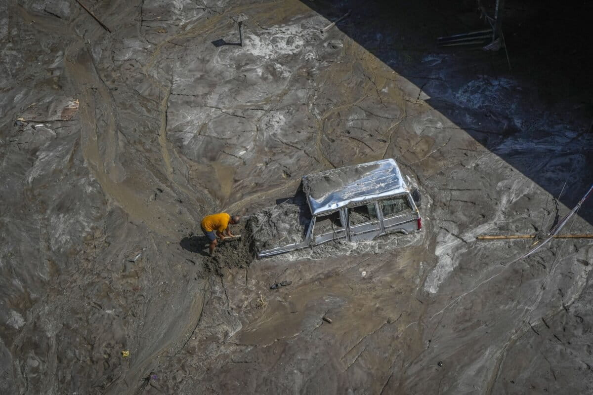 A man attempts to recover a vehicle submerged in mud following floods along the Teesta River in 2023. (AP Photo/Anupam Nath)