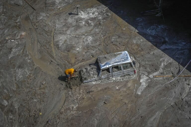 A man attempts to recover a vehicle submerged in mud following floods along the Teesta River in 2023. (AP Photo/Anupam Nath)