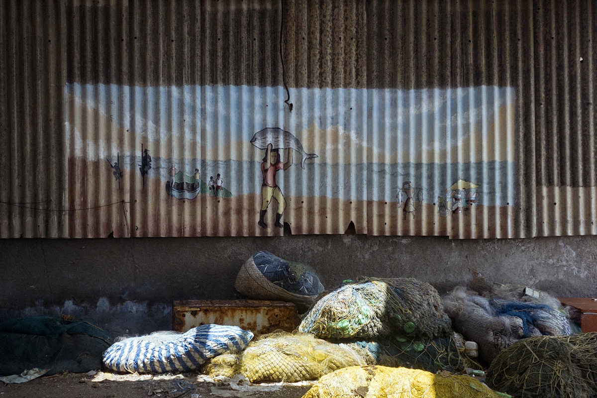 A mural at Neendakara fishing dockyard in Kollam, Kerala showing a fisherman carry a big fish. Image by Leo Paapam/Mongabay.