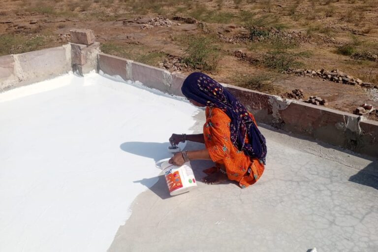 अपने छत पर व्हाइट पेंट करती पिंकी देवी। तस्वीर सौजन्य – महिला हाउसिंग ट्रस्ट