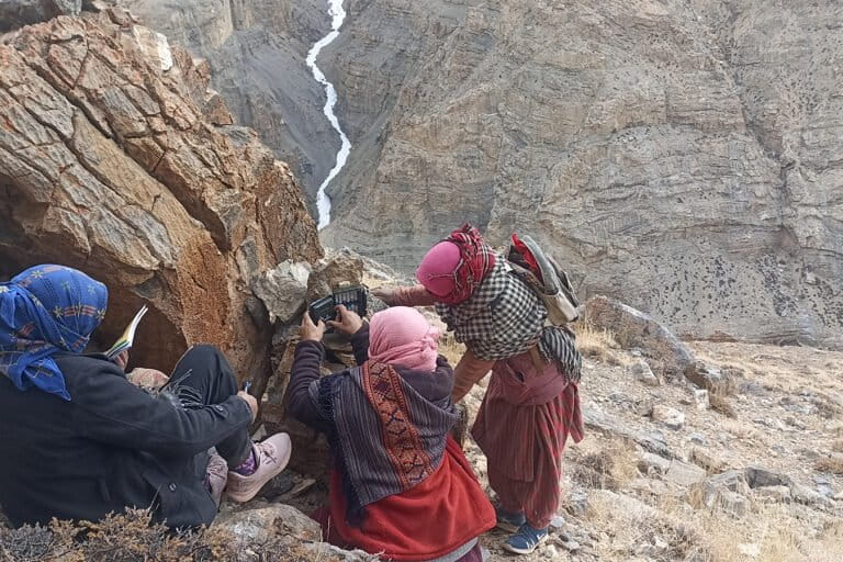 स्पीति घाटी की खड़ी ढलान पर किब्बर गाँव की महिलाएं हिम तेंदुआ सर्वेक्षण के दौरान कैमरा ट्रैप लगाती हुईं। तस्वीर साभार: नेचर कंज़र्वेशन फाउंडेशन और हिमाचल प्रदेश वन विभाग