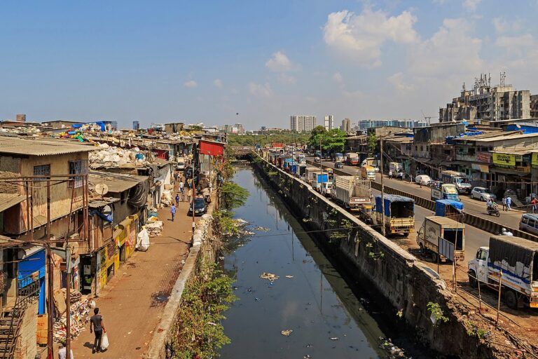 मुंबई के धारावी में अनौपचारिक बस्तियां। स्टडी में पाया गया कि धारावी, संगम नगर, शिवाजी नगर और अन्य कम आय वाले इलाकों में जमीन अमीर इलाकों की तुलना में ज्यादा तेजी से धंस रही है। इसका कारण इन बस्तियों में अनौपचारिक घरों की अधिक संख्या और इमारतों की पतली नींवें मानी गई हैं। तस्वीर: A. Savin / विकिमीडिया कॉमन्स (Public Domain)